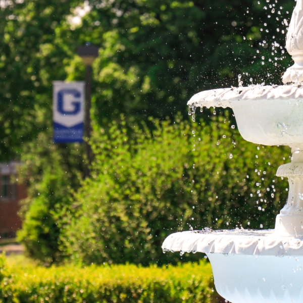 A close up of the fountain in the Dora Heflin Garden. Water droplets splash in the air as water cascades down the fountain.
