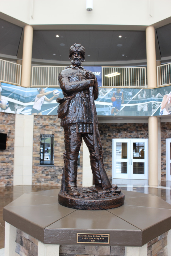 A bronze statue of a pioneer, complete with coonskin cap, buckskins, and an old-timey hunting rifle. The statue stands in the center of the athletic center foyer.