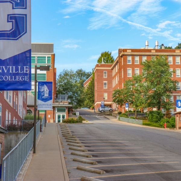 A view of campus from just outside of Goodwin Hall. The shot shows the main street, lined with bright blue GSC banners. It's a bright summer day.
