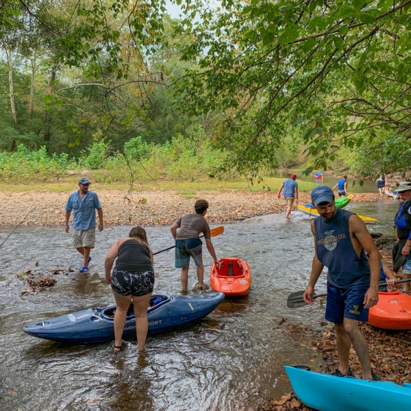 Students are busy putting kayaks into a placid river. The GSC student activities group often leads outdoor excursions.