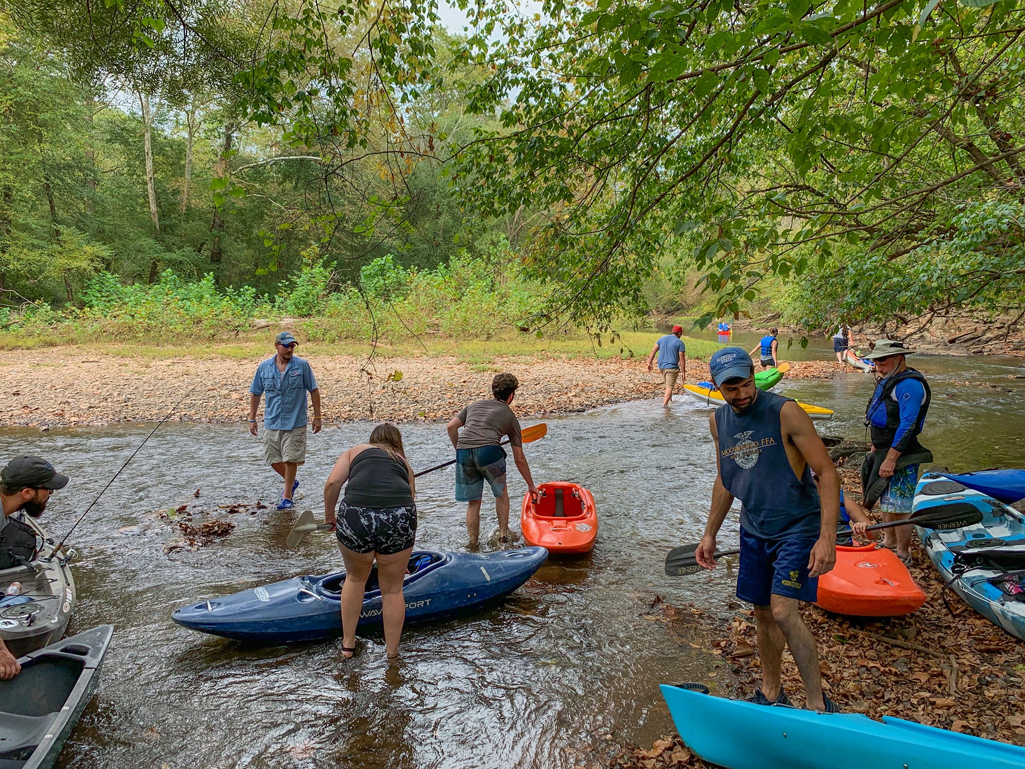 Students are busy putting kayaks into a placid river. The GSC student activities group often leads outdoor excursions.
