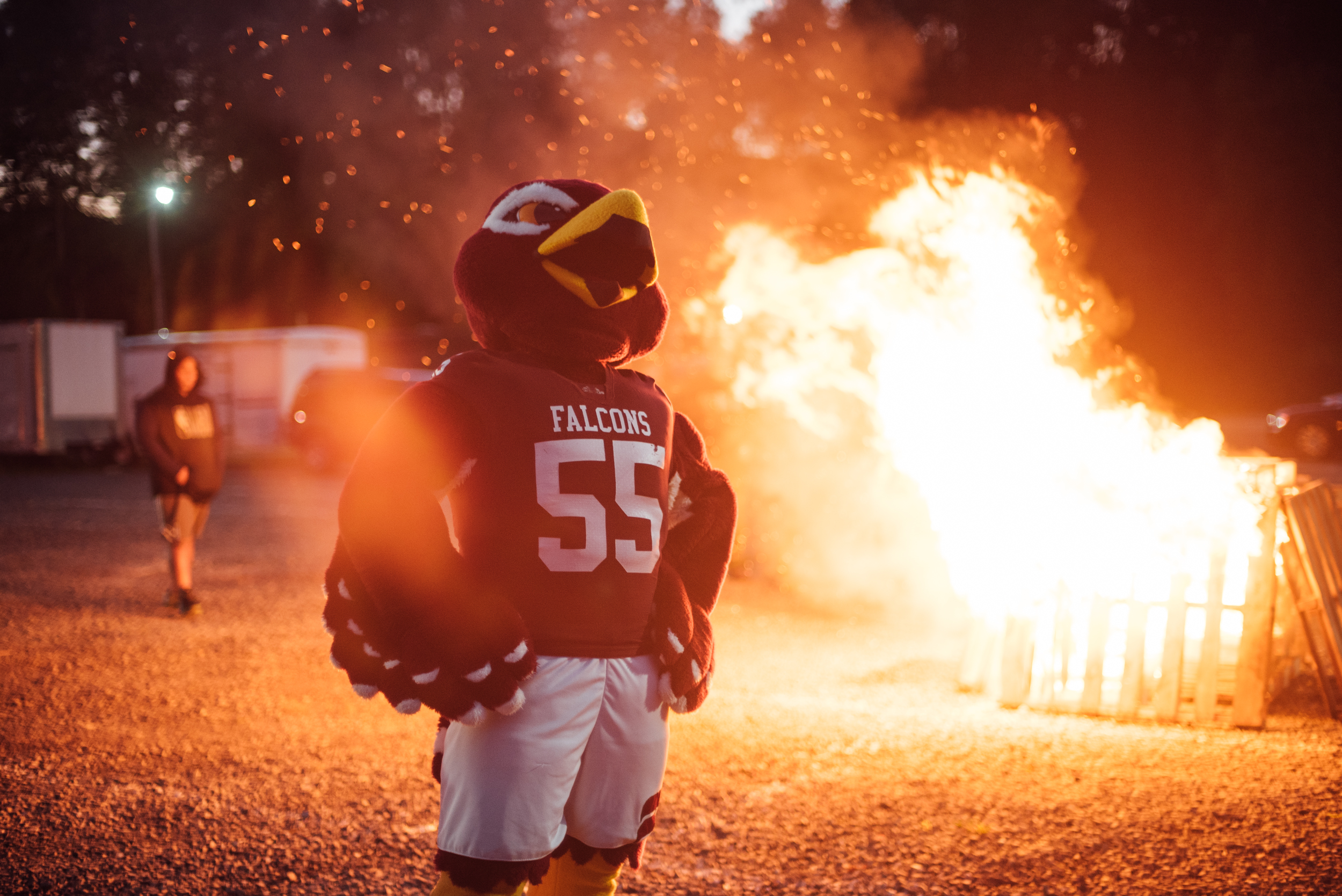 The FSU mascot, Freddie the Falcon, stands in front of a blazing bonfire at night
